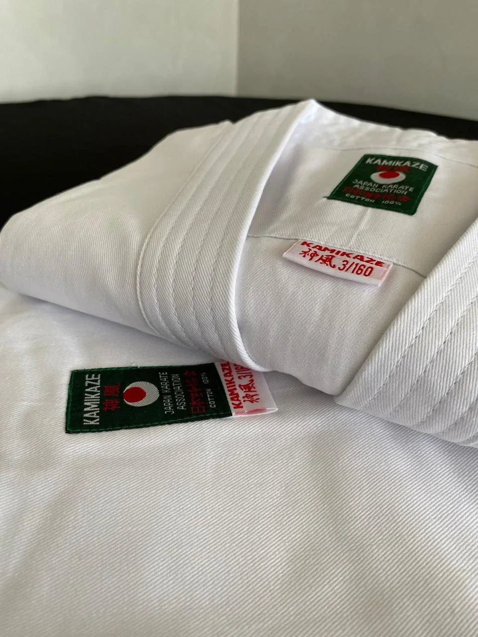 White karate gi uniform folded, with Kamikaze Japan Karate Association cotton label visible