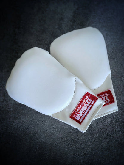 Pair of white karate sparring gloves with red Kamikaze label on dark surface